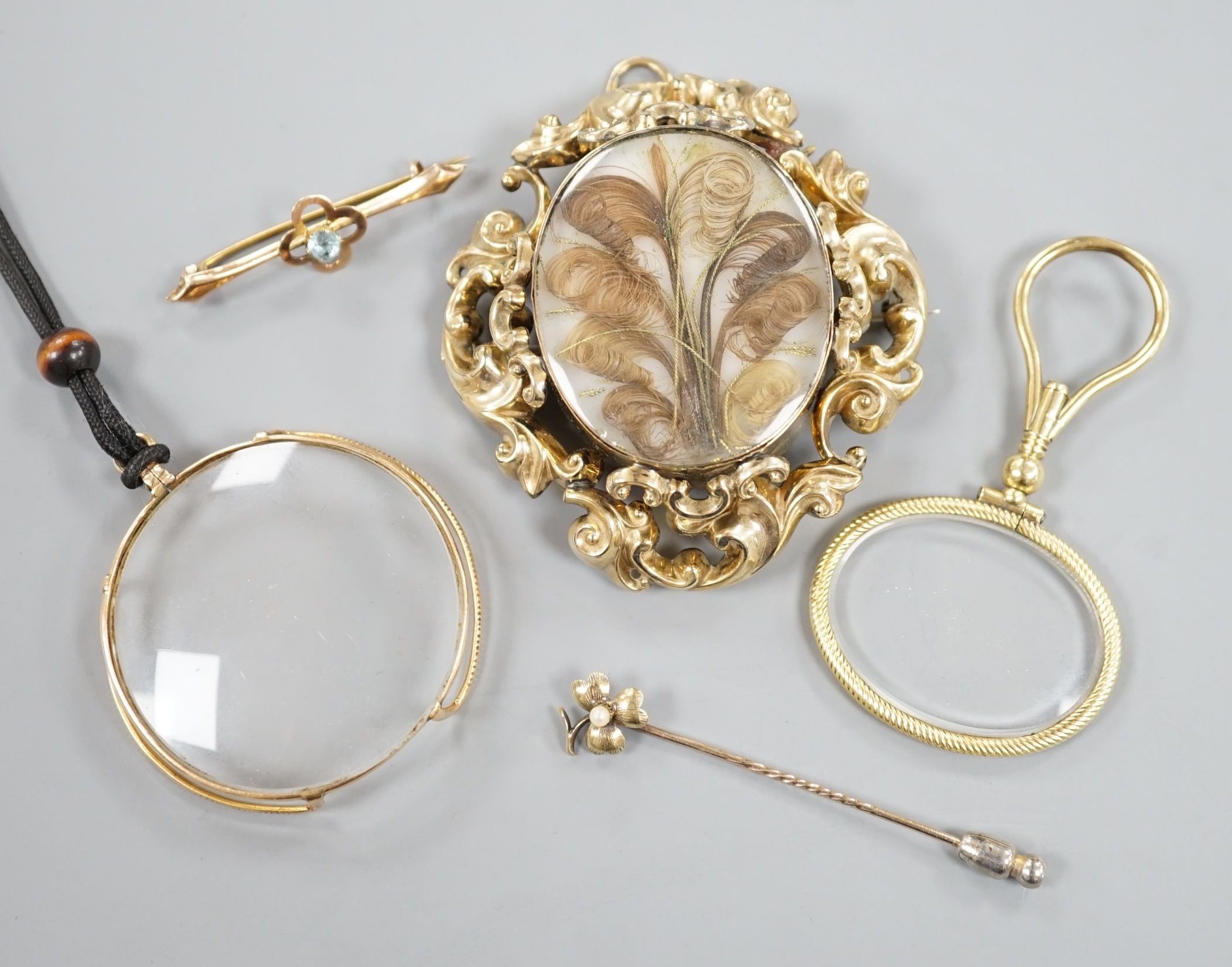 A Victorian yellow metal mounted plaited hair mourning brooch, 6cm, a yellow metal mounted magnifying glass, a similar stick pin and eye glass and a 9ct and gem set bar brooch.